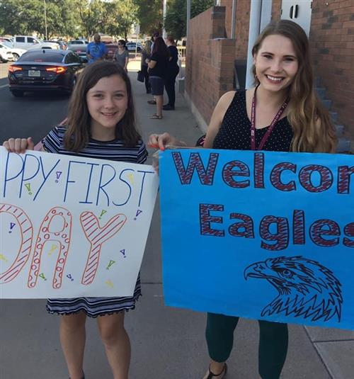 students and teachers hold welcome signs